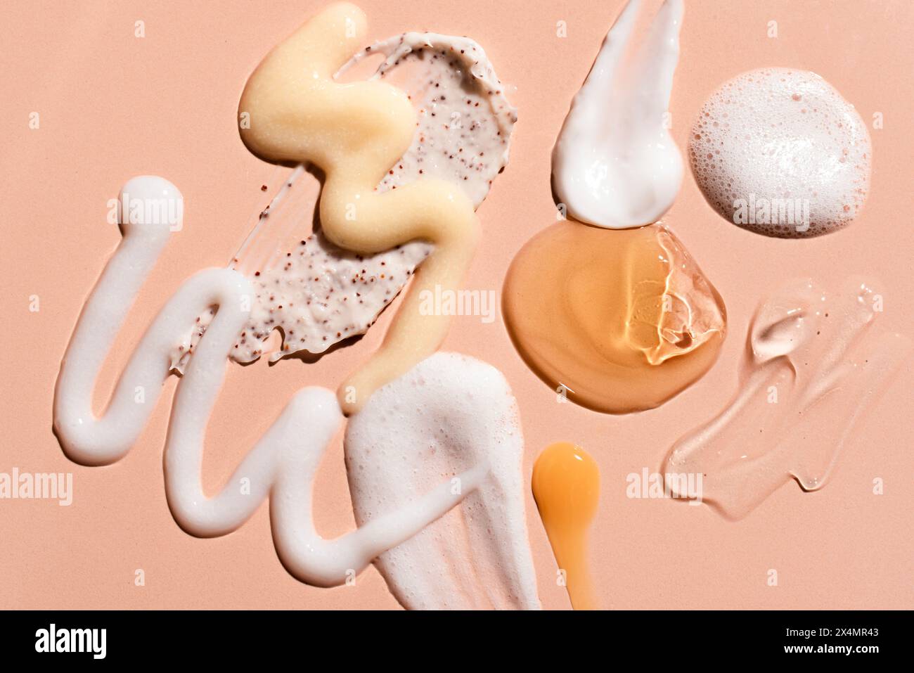 Gel de produits cosmétiques et maculage de crème sur fond rose beige. Produits de beauté pour les soins de la peau du visage et du corps : hydratant, essence de sérum, nettoie Banque D'Images