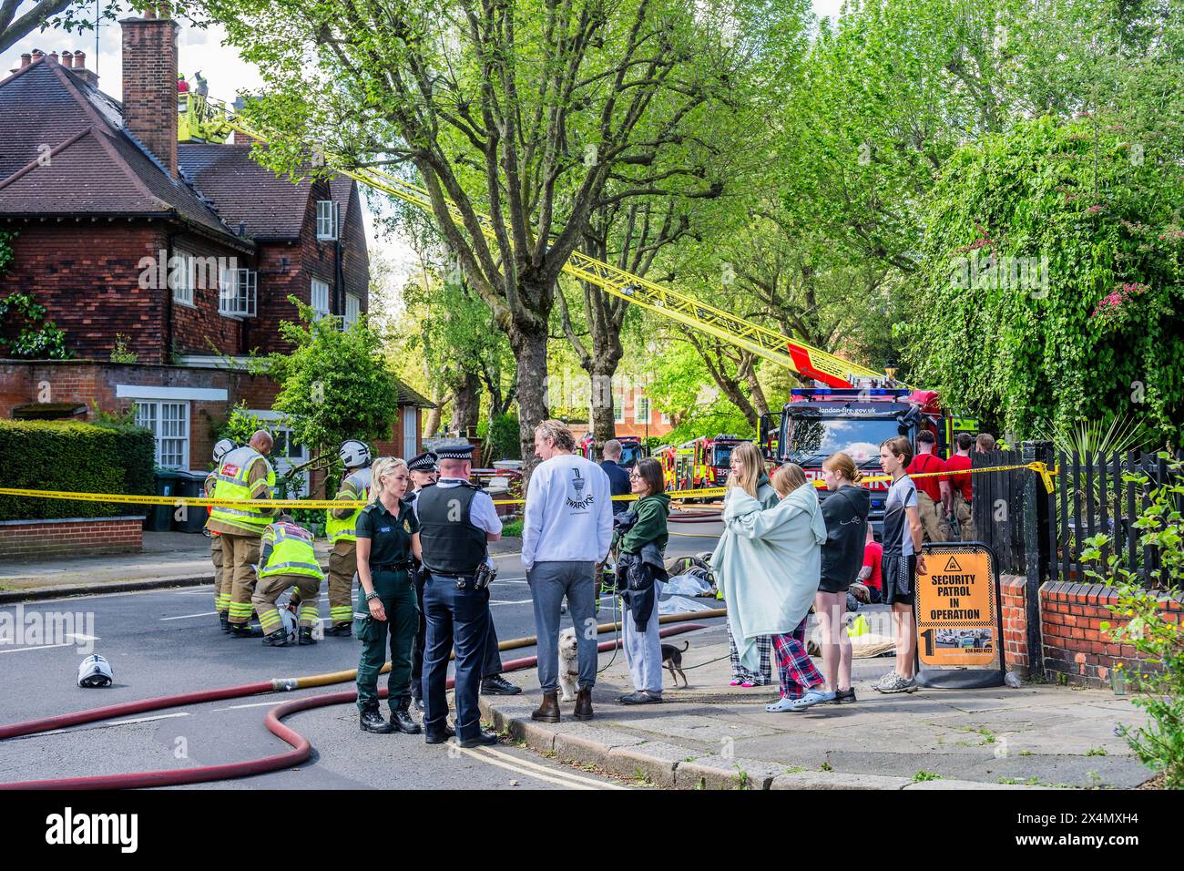 Londres, Royaume-Uni. 4 mai 2024. De nombreux pompiers, ambulances et policiers assistent à un incendie dans une grande maison sur Elsworthy Road dans la région de Primrose Hill. L'incendie semble avoir été faible et il est éteint et les équipes d'urgence commencent à se disperser alors que la famille déplacée regarde. Dix pompiers et environ 70 pompiers ont répondu. La moitié du deuxième étage, dans une maison individuelle de trois étages, a été endommagée par l'incendie. L'une des échelles de 32 m de la brigade a été déployée avec des pompiers de West Hampstead, Paddington, Kentish Town. Crédit Guy Bell/Alamy Live News Banque D'Images