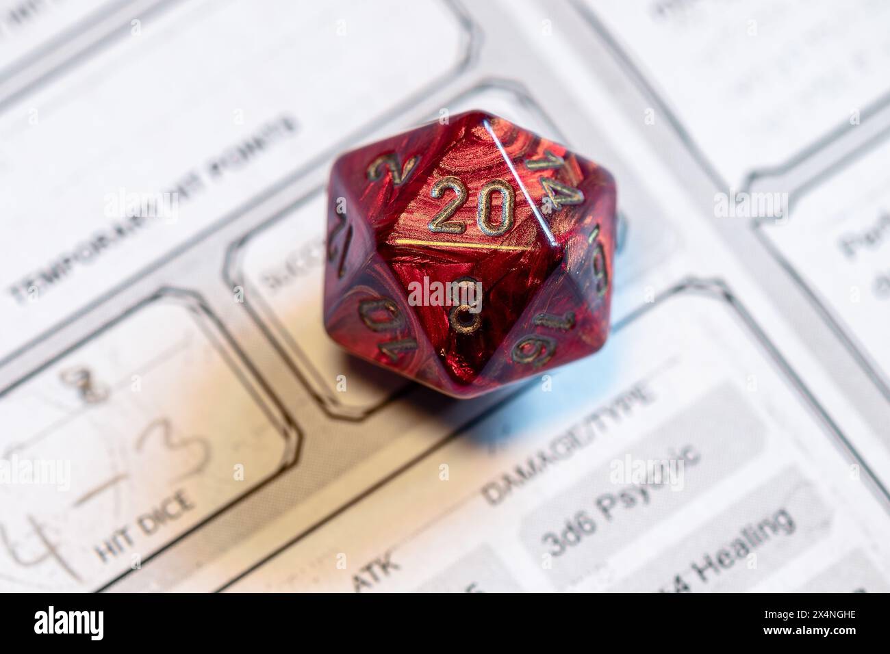 Plan ciblé d'un dé rouge D20 sur une feuille de personnage, mettant en évidence les moments critiques des jeux de rôle sur table. Banque D'Images