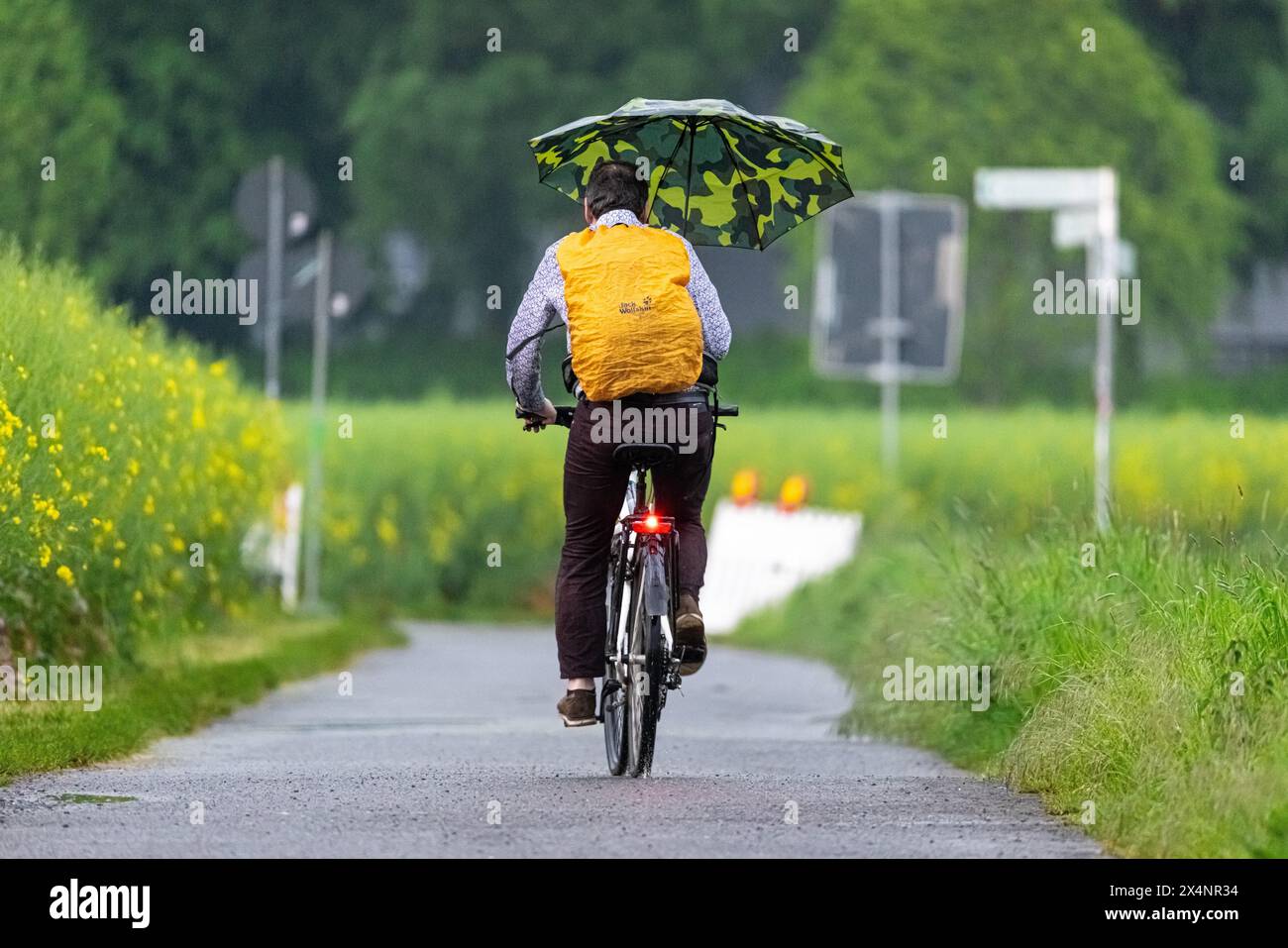 Un cycliste roule le long d'une voie de campagne sous de fortes pluies dans le nord-ouest de Francfort-sur-le-main, Francfort-sur-le-main, Hesse, Allemagne, Europe Banque D'Images