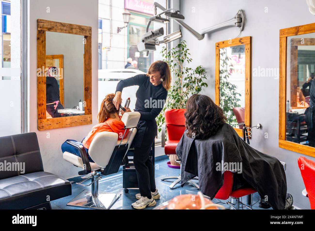 Photo pleine longueur d'un salon de beauté complet avec coiffeur assistant les clients Banque D'Images