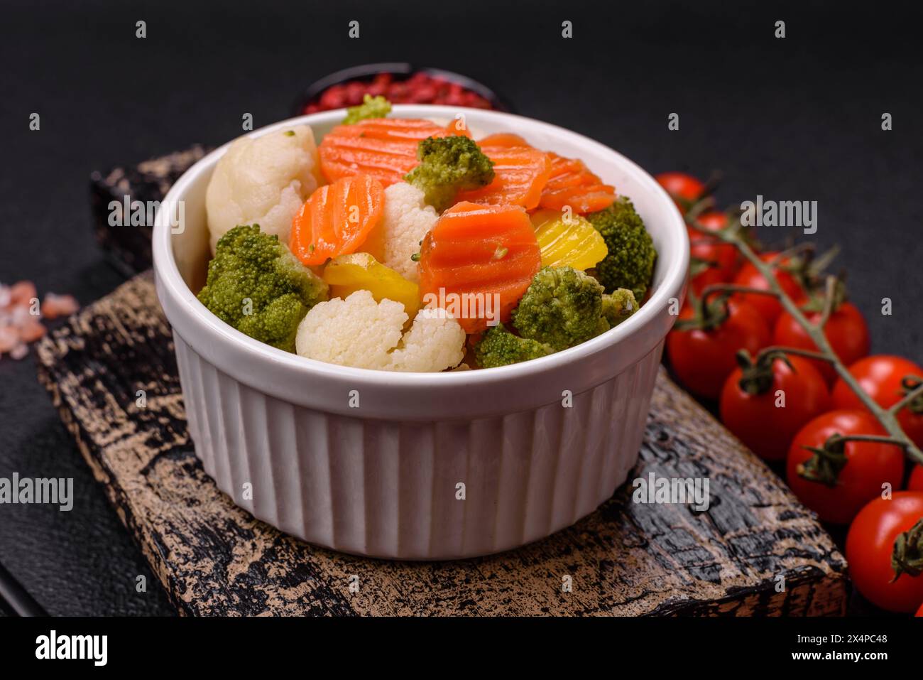 Délicieux légumes frais brocoli, chou-fleur, carottes cuits à la vapeur avec du sel, des épices et des herbes sur un fond Uni Banque D'Images
