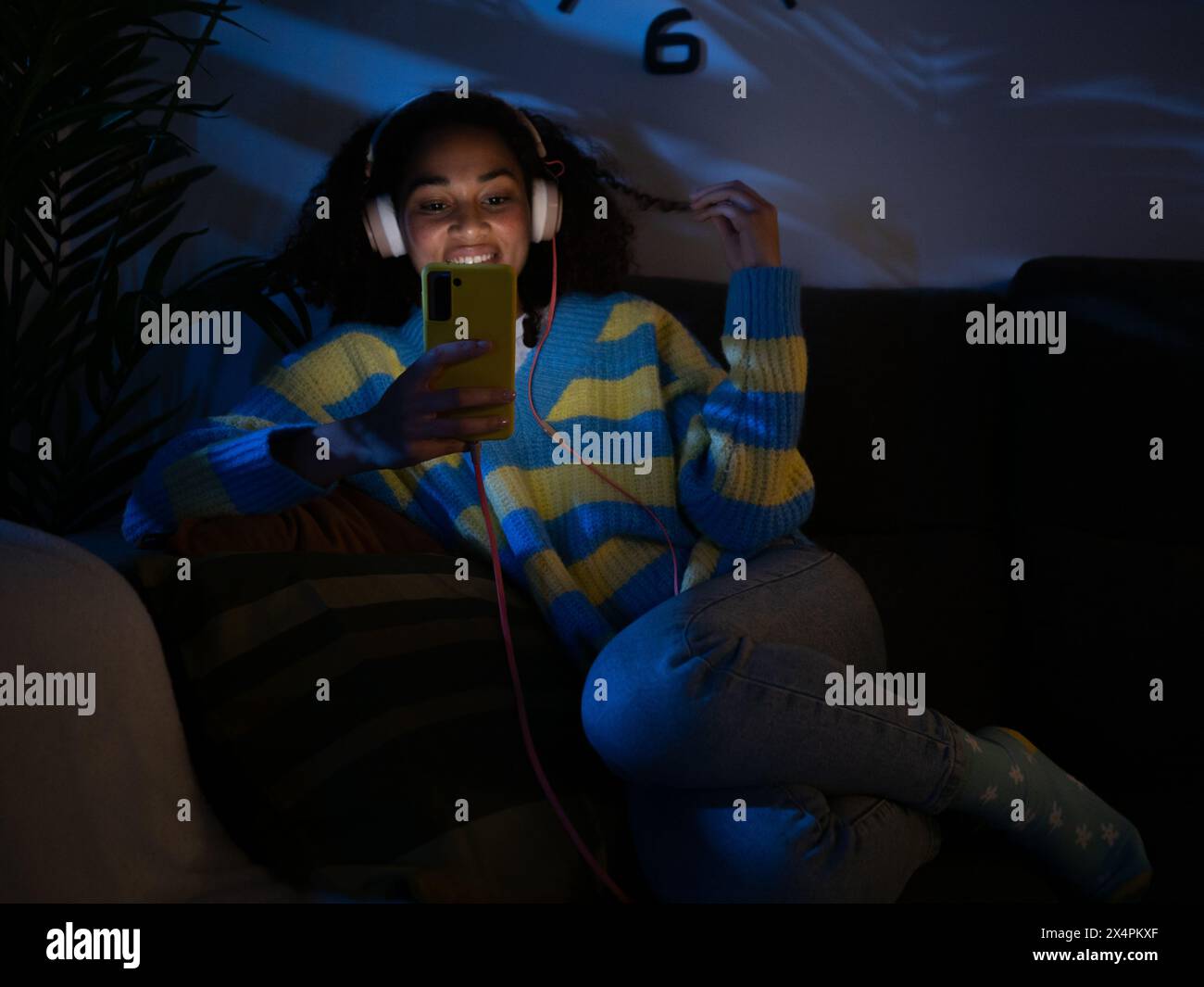 Jeune femme afro-américaine discutant assise sur un canapé la nuit dans un appartement Banque D'Images