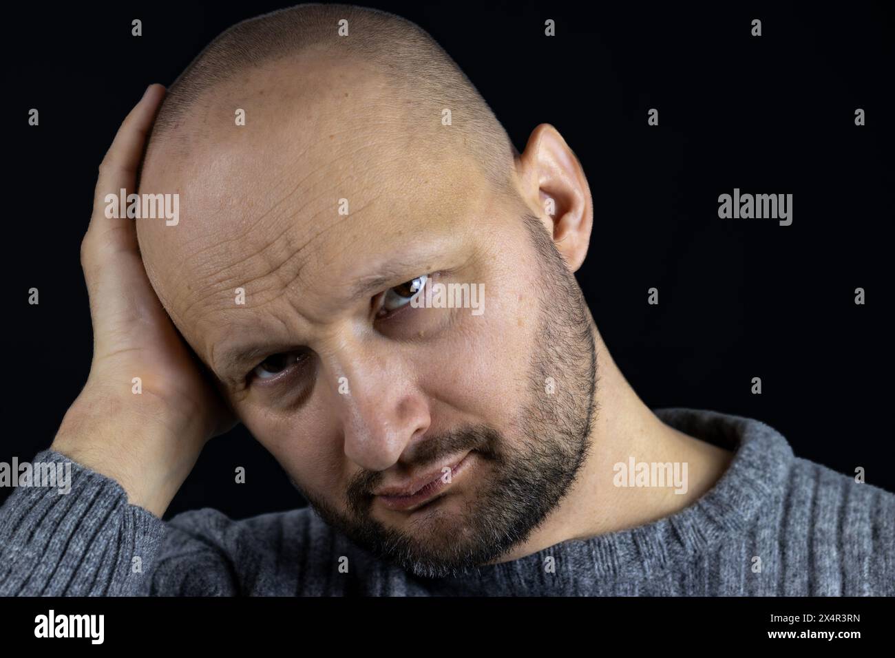 Voici un portrait saisissant d'un homme de 45 ans, profondément dans la pensée, reposant sa tête sur sa main et regardant attentivement la caméra. Banque D'Images