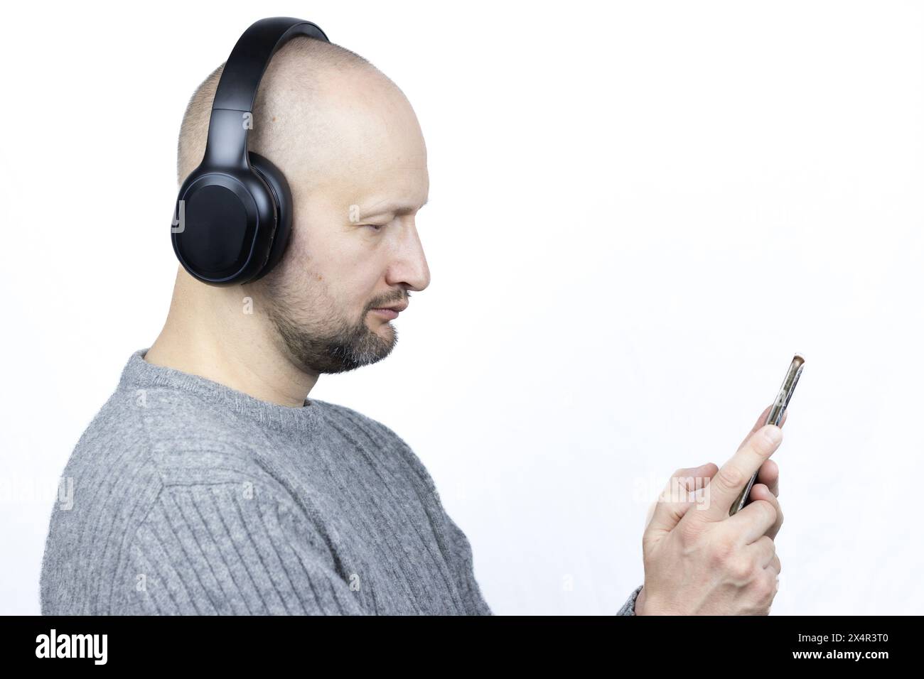 C'est un portrait captivant d'un homme, placé sur un fond blanc dur. Il est vêtu d'un pull en laine grise finement tricoté Banque D'Images