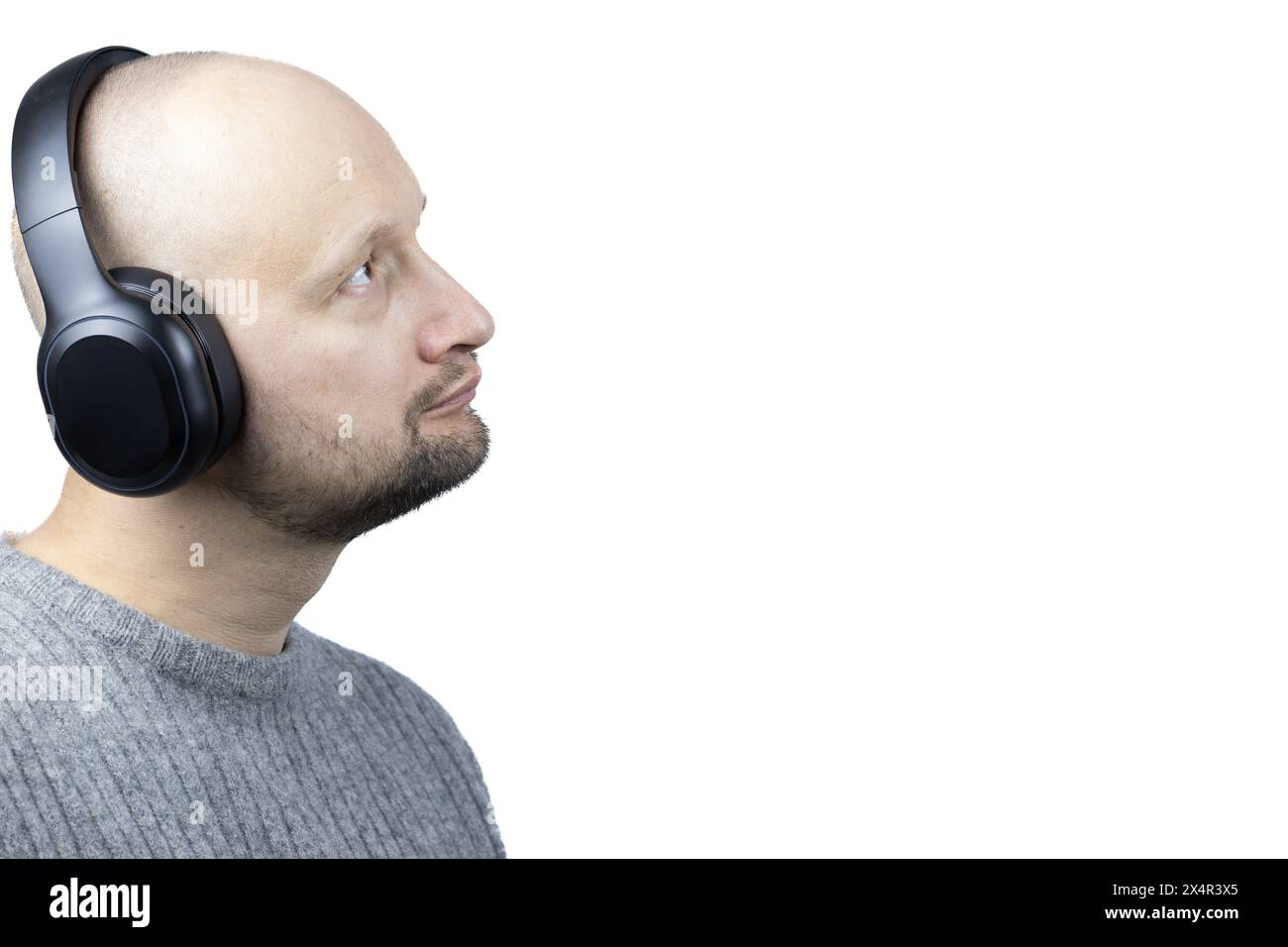 C'est un portrait captivant d'un homme, placé sur un fond blanc dur. Il est vêtu d'un pull en laine grise finement tricoté, son regard dirigé vers le haut Banque D'Images