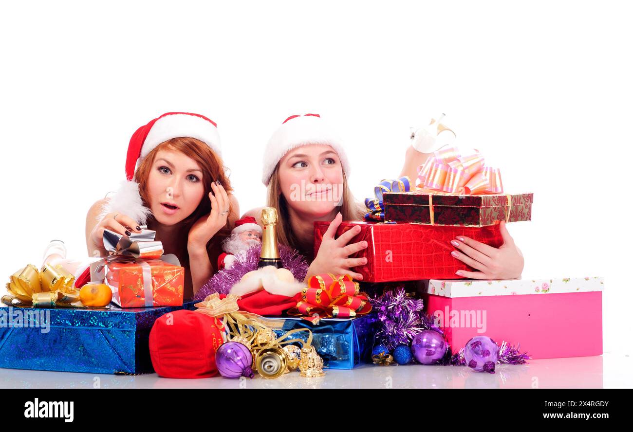 deux jolies femmes en vêtements de noël gisent sur le sol blanc avec des cadeaux, isolées sur blanc Banque D'Images