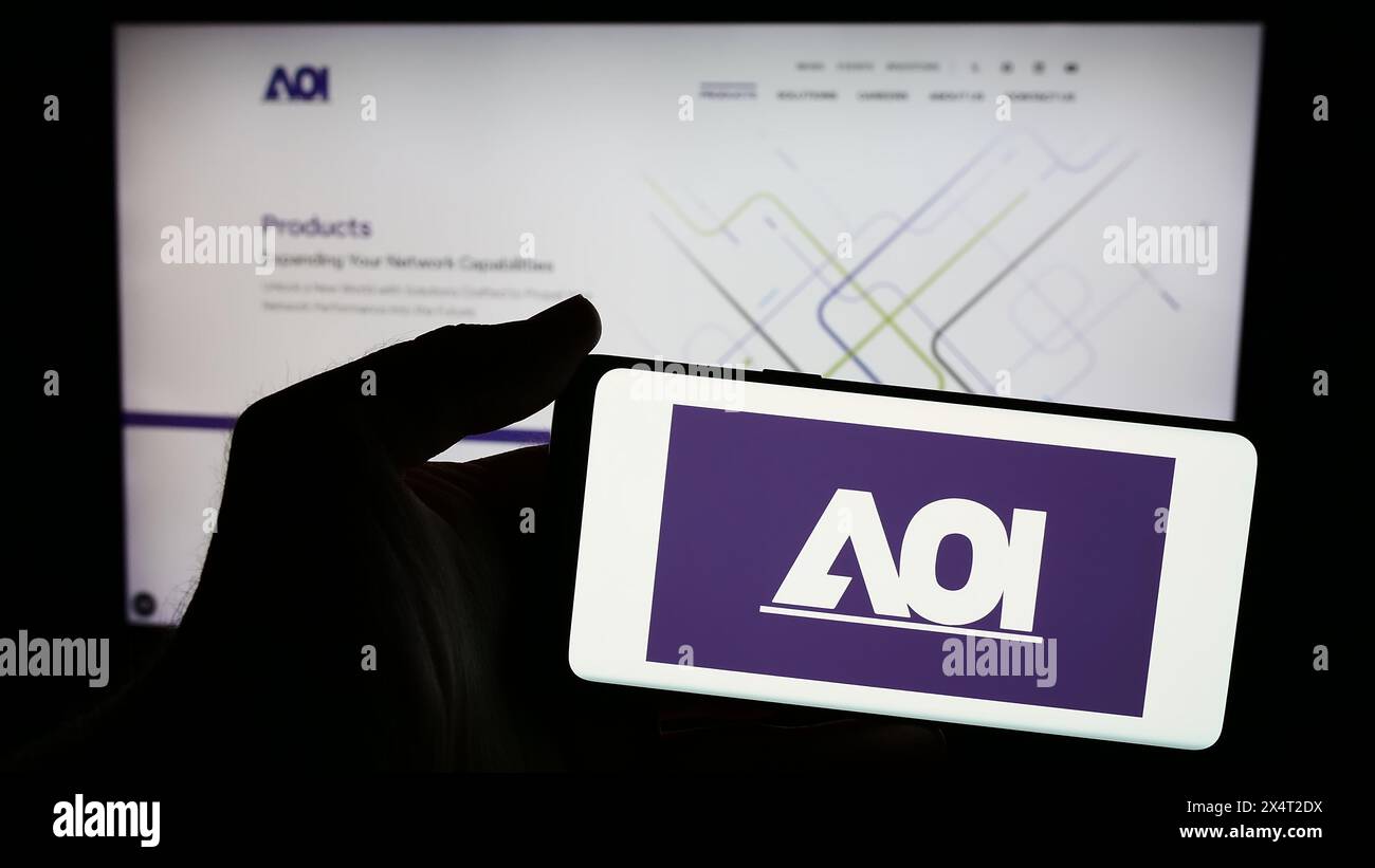 Personne tenant un smartphone avec le logo de la société américaine Applied Optoelectronics Inc (AOI) en face du site Web. Concentrez-vous sur l'affichage du téléphone. Banque D'Images