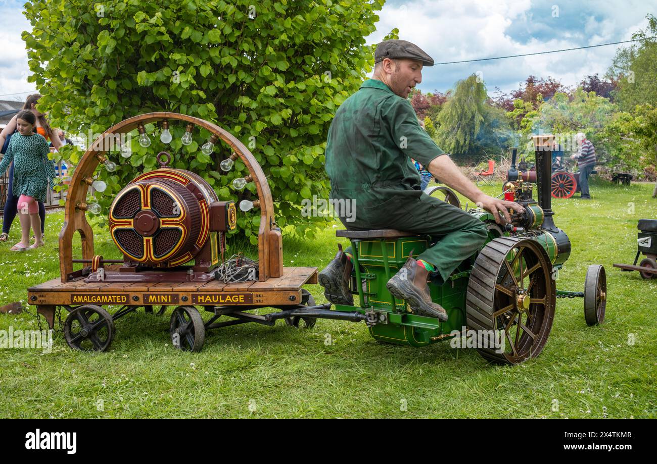 Un passionné conduit un moteur de traction miniature à vapeur tirant une remorque avec une dynamo électrique au South Downs Steam Railway, Pulborough, Wes Banque D'Images