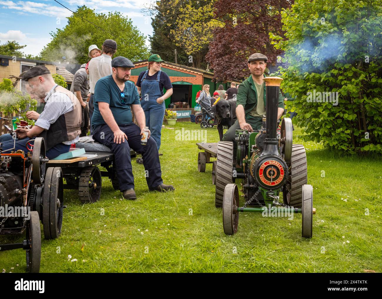 Les passionnés admirent un homme conduisant un moteur de traction miniature à vapeur tirant une remorque avec son chien noir au South Downs Steam Railway, Pulborou Banque D'Images