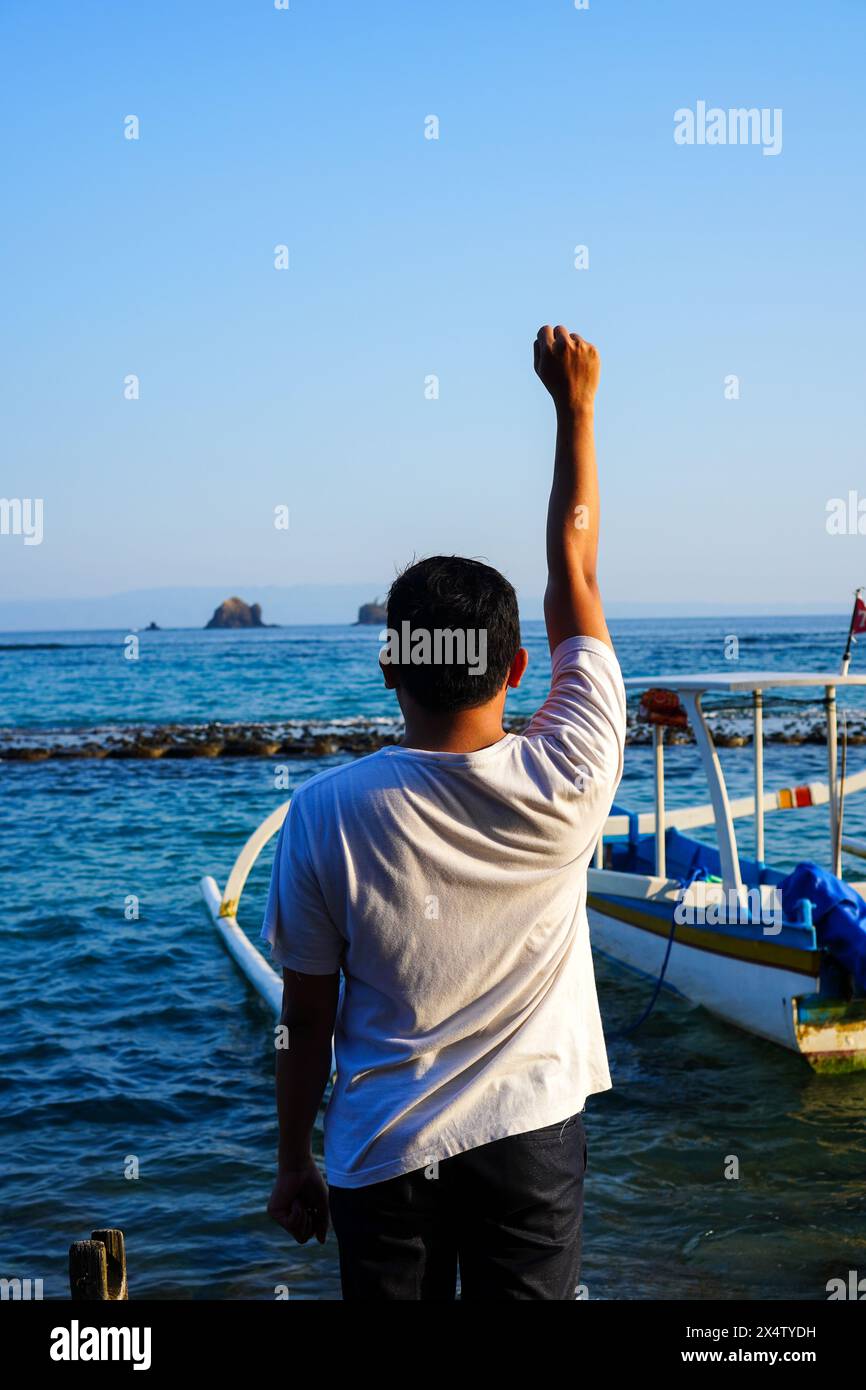 Vue arrière de l'homme célébrant la victoire ou de bons résultats tout en regardant la mer Banque D'Images