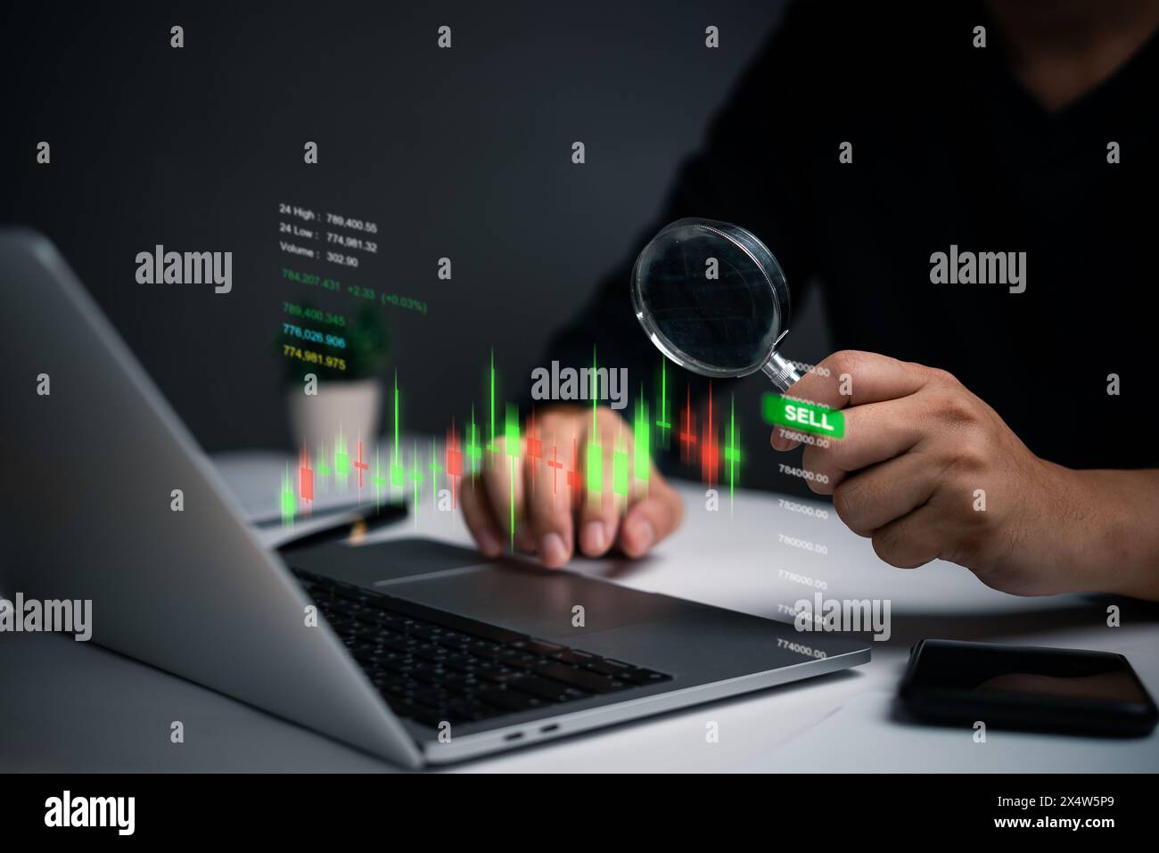 Une personne examine les indicateurs boursiers sur un écran d'ordinateur portable à l'aide d'une loupe. L'accent mis sur des points de données spécifiques suggère une analyse détaillée Banque D'Images