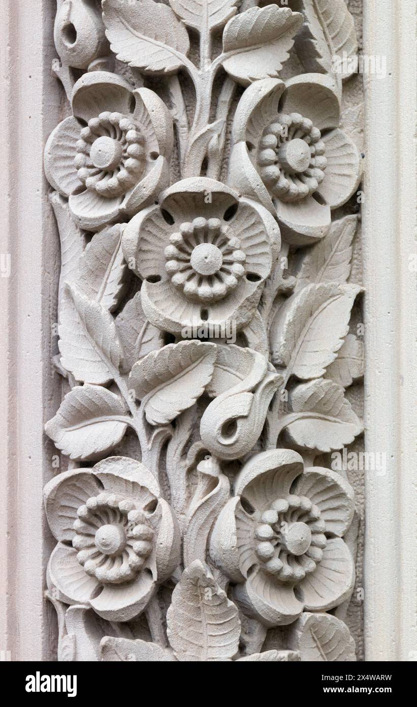 Colonne ornée de feuilles et de fleurs ornées dans un vieux mur de pierre. Banque D'Images