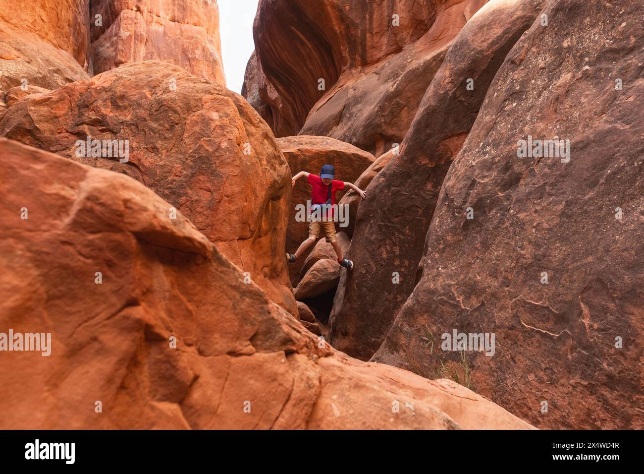 Jeune randonneur grimpant à travers le chemin étroit dans Fiery Furnace dans le parc national d'Arches, Utah, États-Unis. Banque D'Images