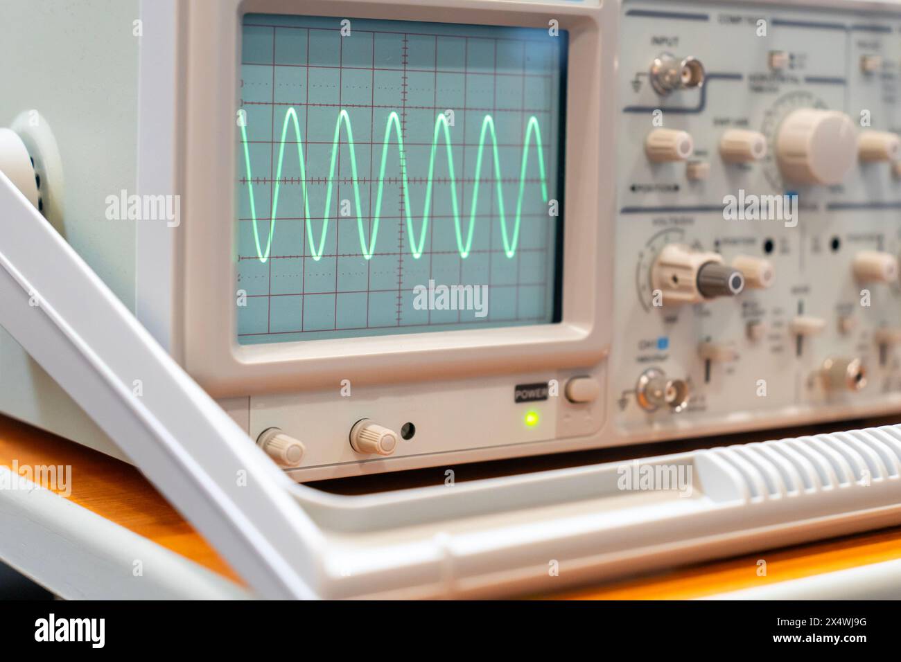 Ondes sinusoïdales vertes sur l'écran d'un oscilloscope à plusieurs boutons Banque D'Images