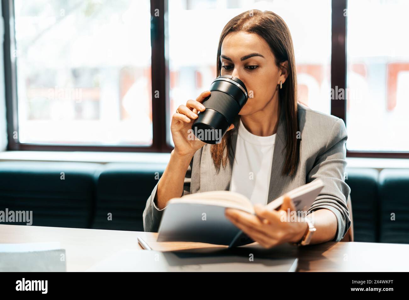 femme travaillant dans un bureau buvant du café dans une bouteille thermos Banque D'Images