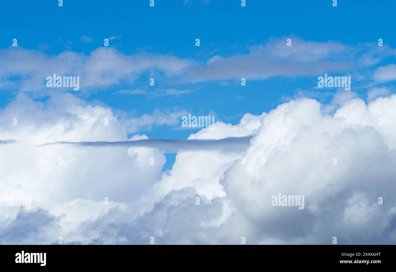 Le ciel bleu électrique est orné de nuages de cumulus blancs moelleux, créant un paysage pittoresque avec des avions volant dans l'atmosphère Banque D'Images