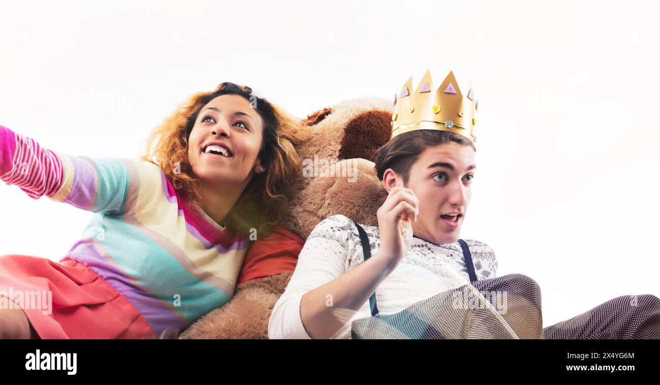 L'image capture un moment amusant avec une jeune femme et un homme vêtus d'une tenue décontractée, entourés de jouets et de ballons, jouant joyeusement Banque D'Images