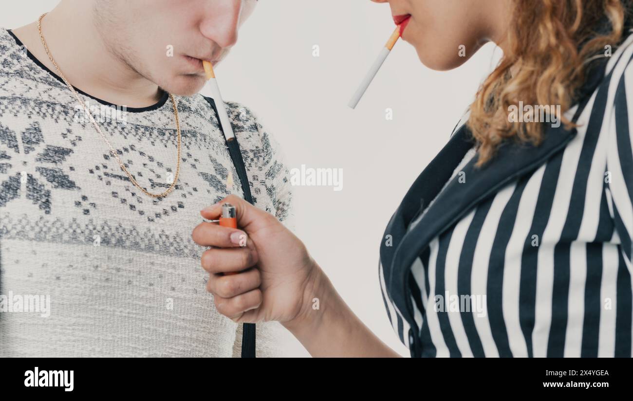 moment critique lorsqu'un jeune homme et une jeune femme succombent à la pression de leurs pairs en fumant, soulignant les dangers de la recherche de l'acceptation sociale Banque D'Images