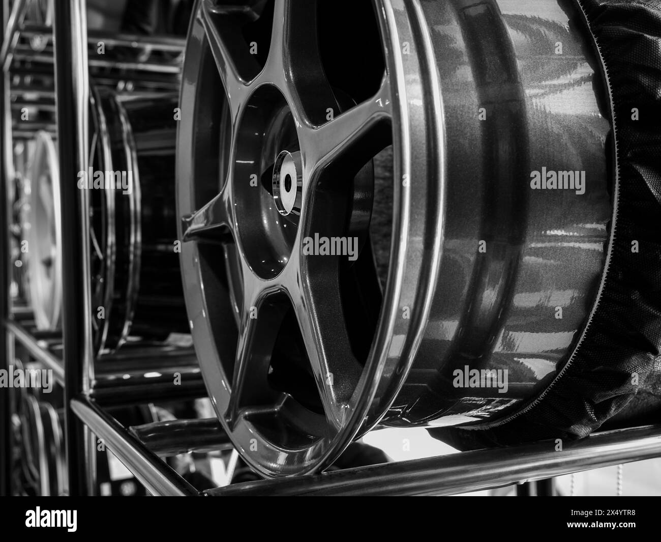Gros plan décoration de jante de roues en alliage sur étagère en métal dans le fond de magasin de pneus. Photographie en noir et blanc de roue mag chromée haute performance auto PA Banque D'Images