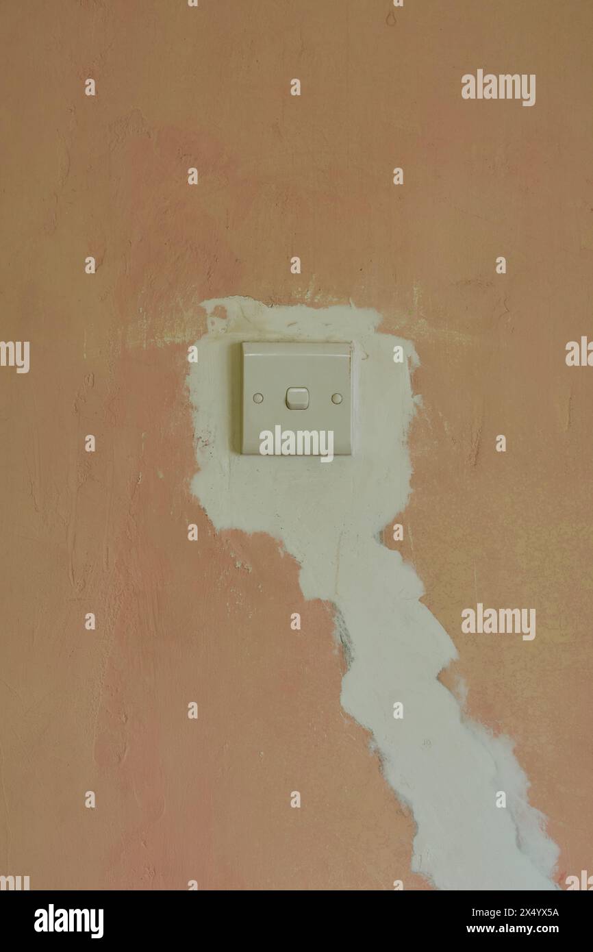réparation de l'installation cachée de fils électriques sur le mur de béton ou de plâtre de ciment autour de l'interrupteur pris avec l'espace de copie Banque D'Images