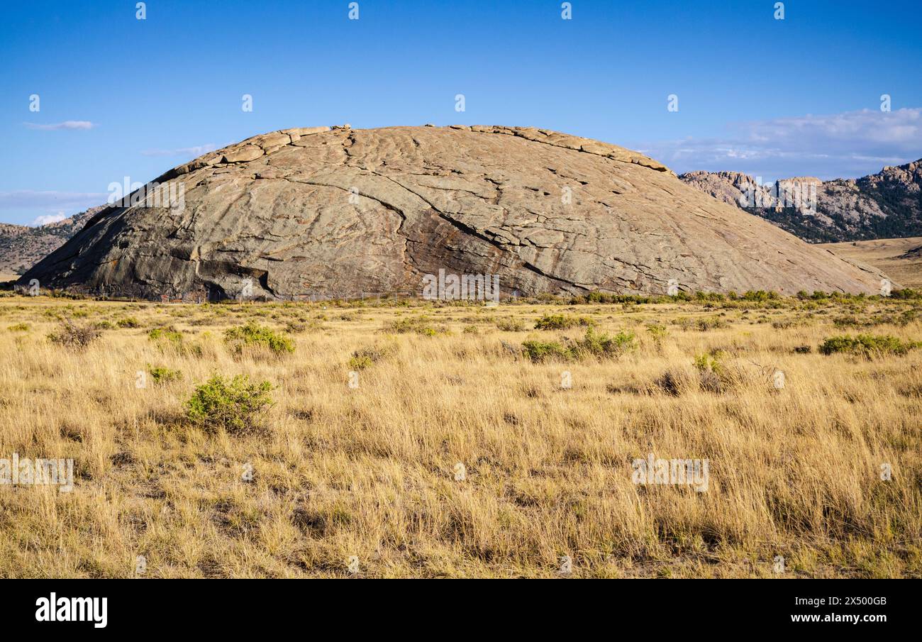 Independence Rock gonfle comme le dos lisse d'une baleine grise au-delà des herbes dorées sèches du site historique d'État d'Independence Rock, Wyoming. Banque D'Images