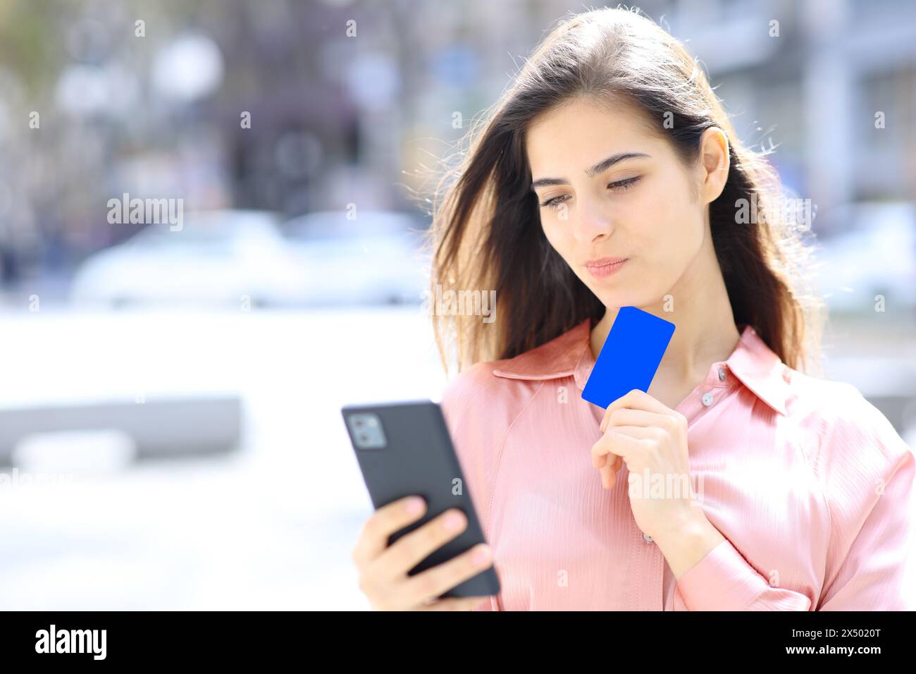Femme achetant en ligne avec carte de crédit et téléphone pensant dans la rue Banque D'Images