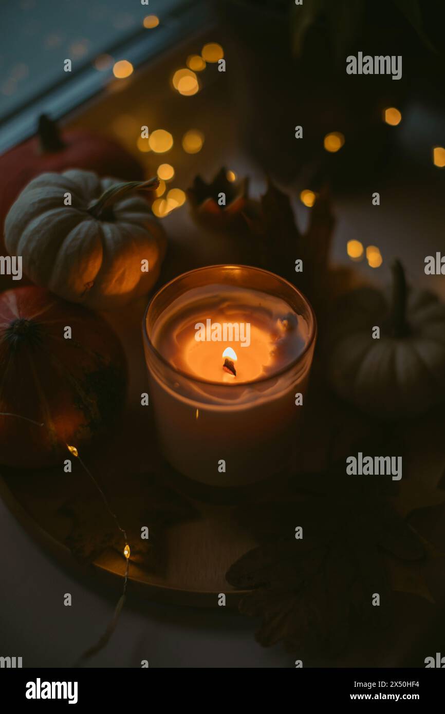 Gros plan d'une bougie incandescente sur une table avec des citrouilles d'automne Banque D'Images