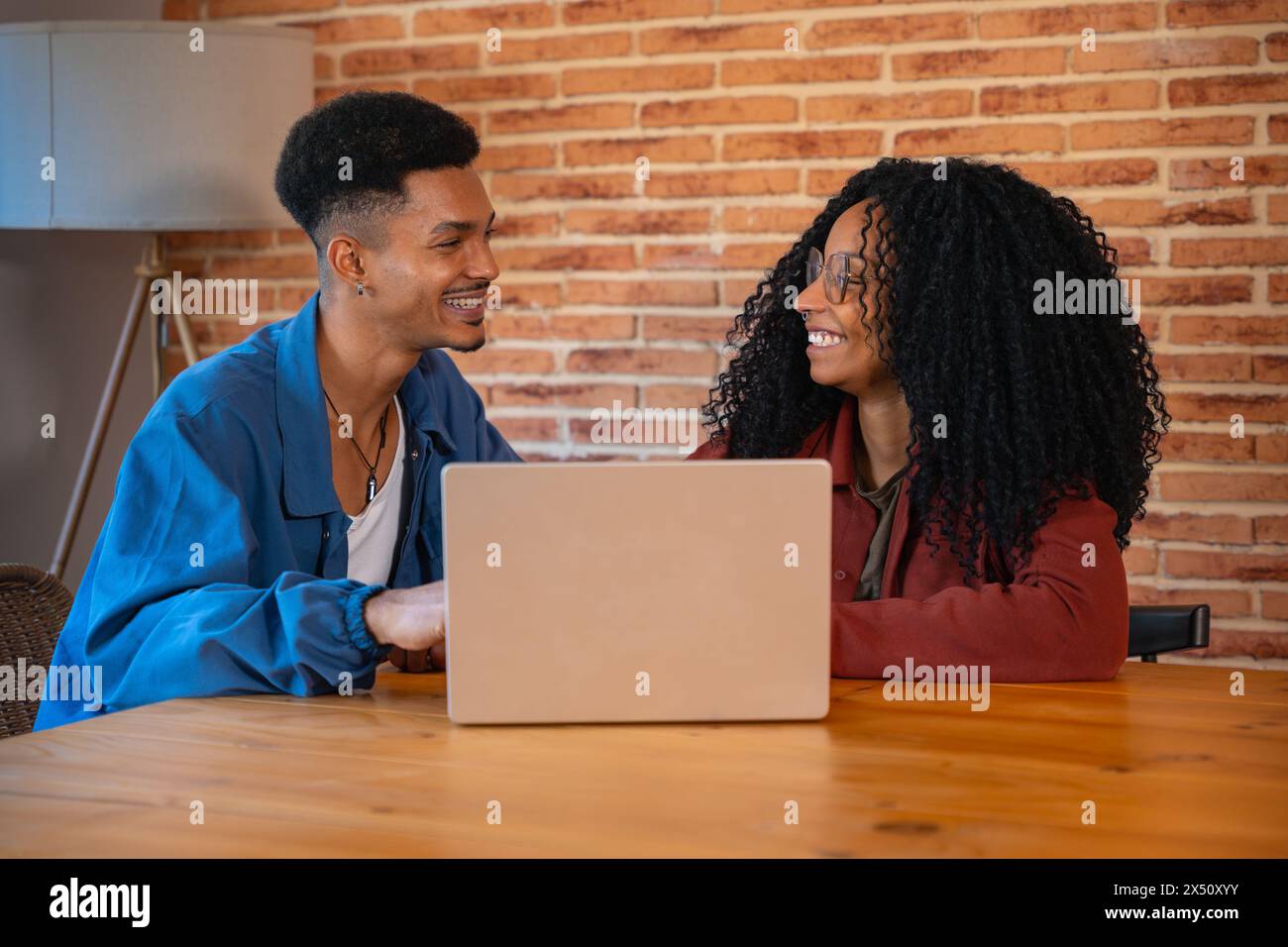 Heureux homme multiethnique et femme conversent et surfent sur Internet sur un ordinateur portable. Banque D'Images