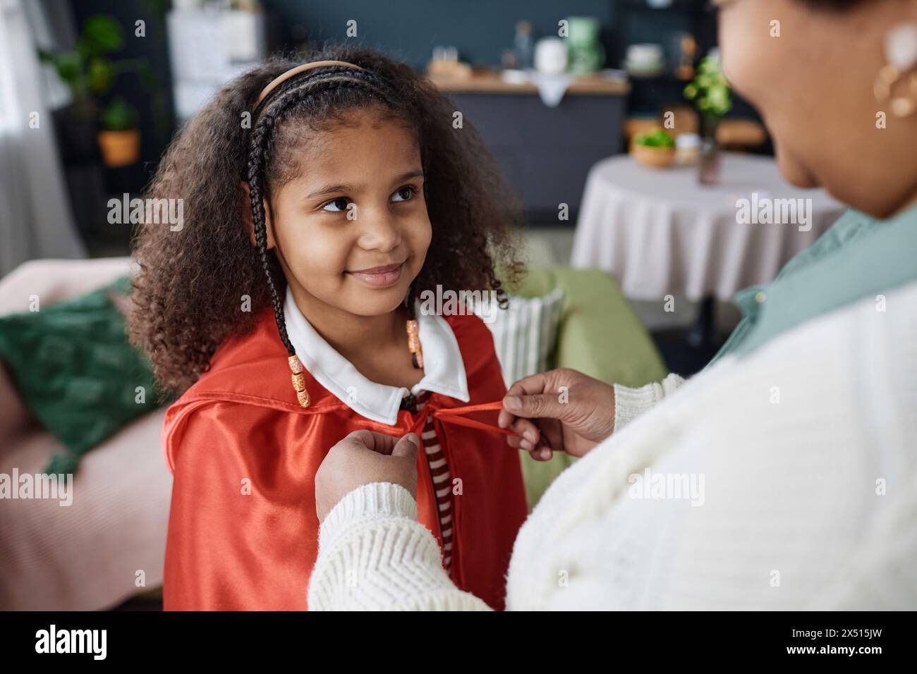 Gros plan à angle élevé de grand-mère aidant la fille noire souriante à s'habiller en costume à l'intérieur Banque D'Images