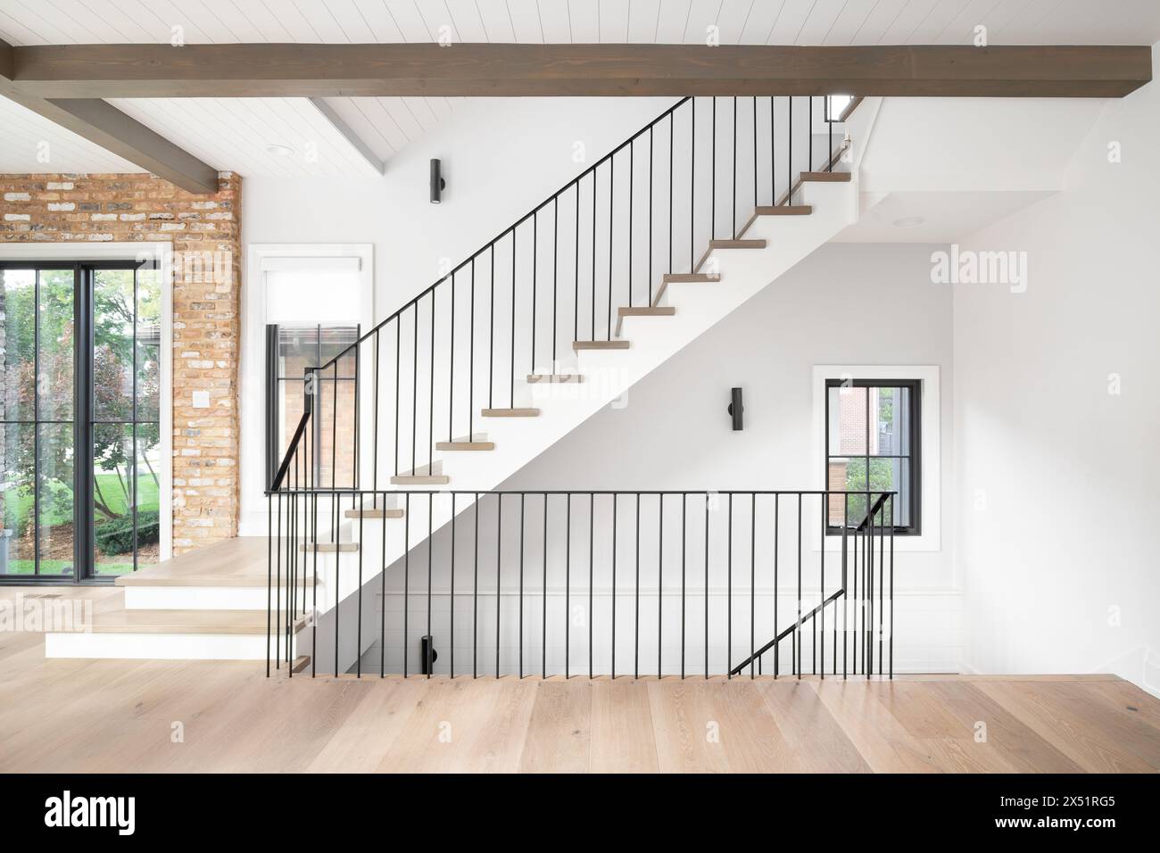 Un bel escalier avec plancher en bois et marches d'escalier, garde-corps en fer forgé, et poutres en bois à travers le plafond avec shiplap. Banque D'Images