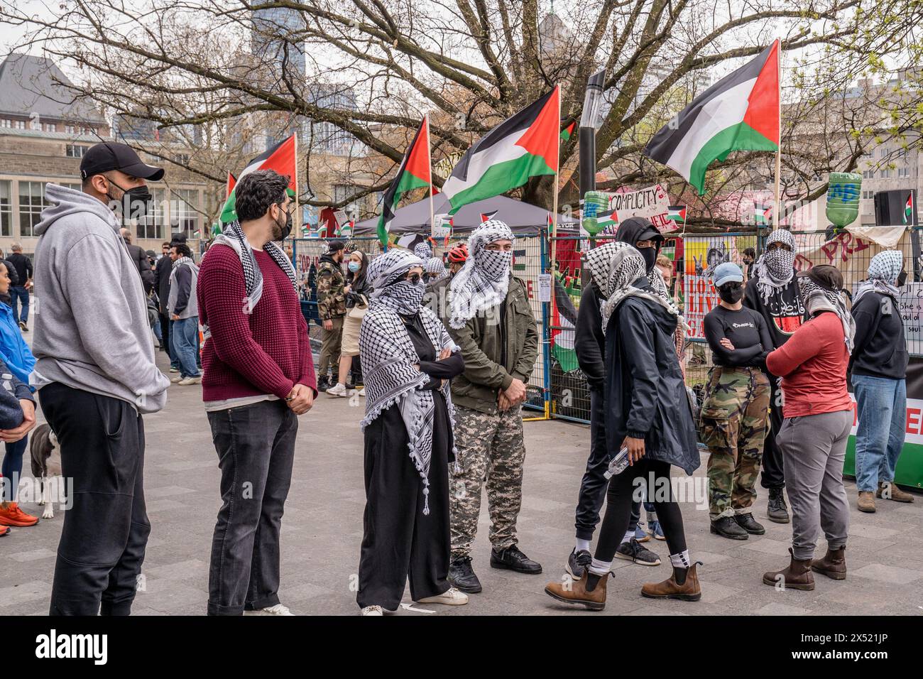 Les étudiants pro-palestiniens masqués forment une chaîne humaine, empêchant les manifestants pro-israéliens de traverser, à l'extérieur du campement que les étudiants ont créé en occupant le King College Circle à l'Université de Toronto pendant le rassemblement. Des campements palestiniens sont établis sur les campus du monde entier, manifestant leur opposition au sionisme et présentant parfois un langage et des panneaux antisémites. Ces incidents ont suscité des débats sur les limites de la liberté d'expression et la montée de l'extrémisme au sein de certains milieux activistes. Banque D'Images