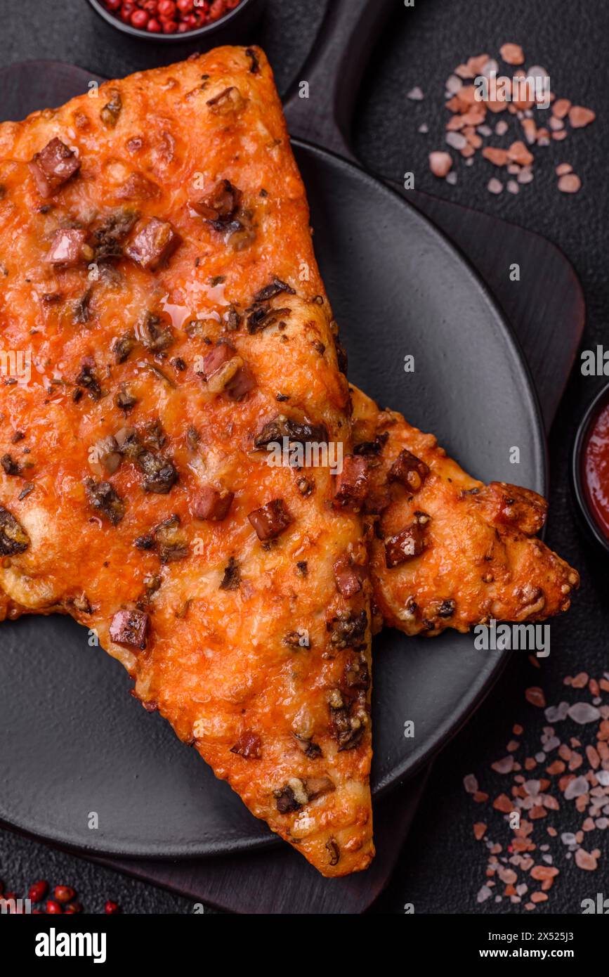 Tranches de délicieuse pizza de rue avec saucisse, champignons, tomates et fromage avec sel et épices sur un fond de béton foncé Banque D'Images