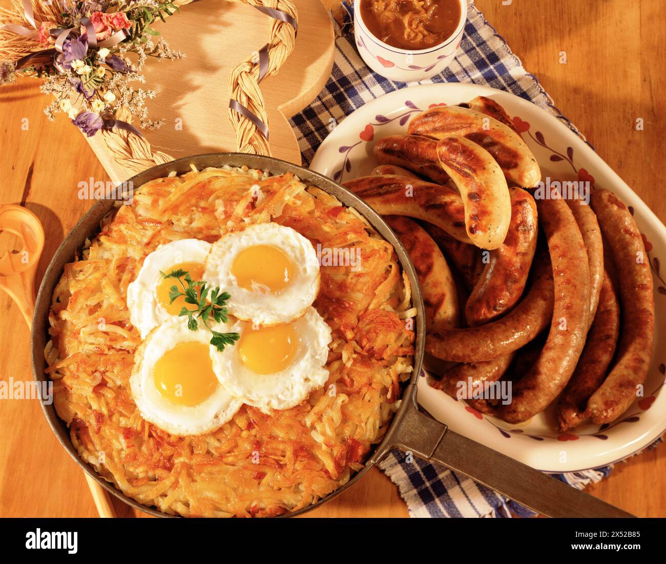 Oeufs frits, rosti en fonte et plateau de saucisses grillées, petit déjeuner d'hiver sur table rustique. Banque D'Images