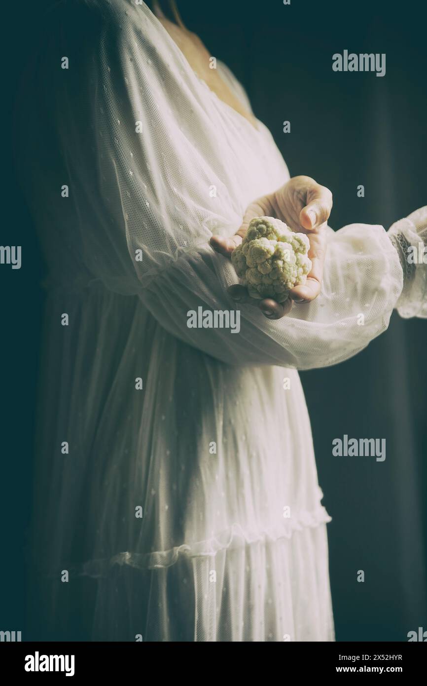 femme en robe blanche de style romantique tenant un chou-fleur dans ses bras, espagne Banque D'Images