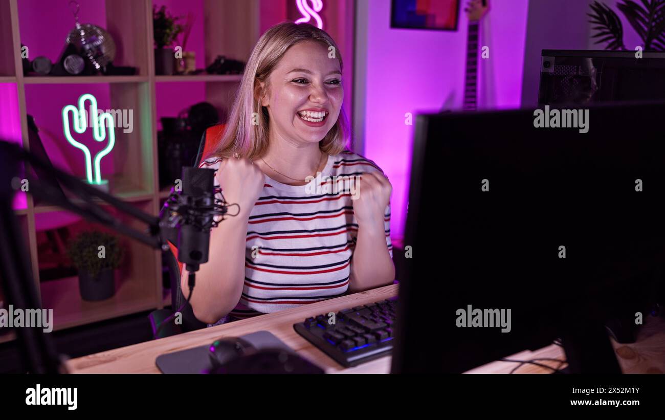 Une femme joyeuse jaillit d'une salle de jeu vibrante, éclairée par des lumières LED multicolores la nuit. Banque D'Images