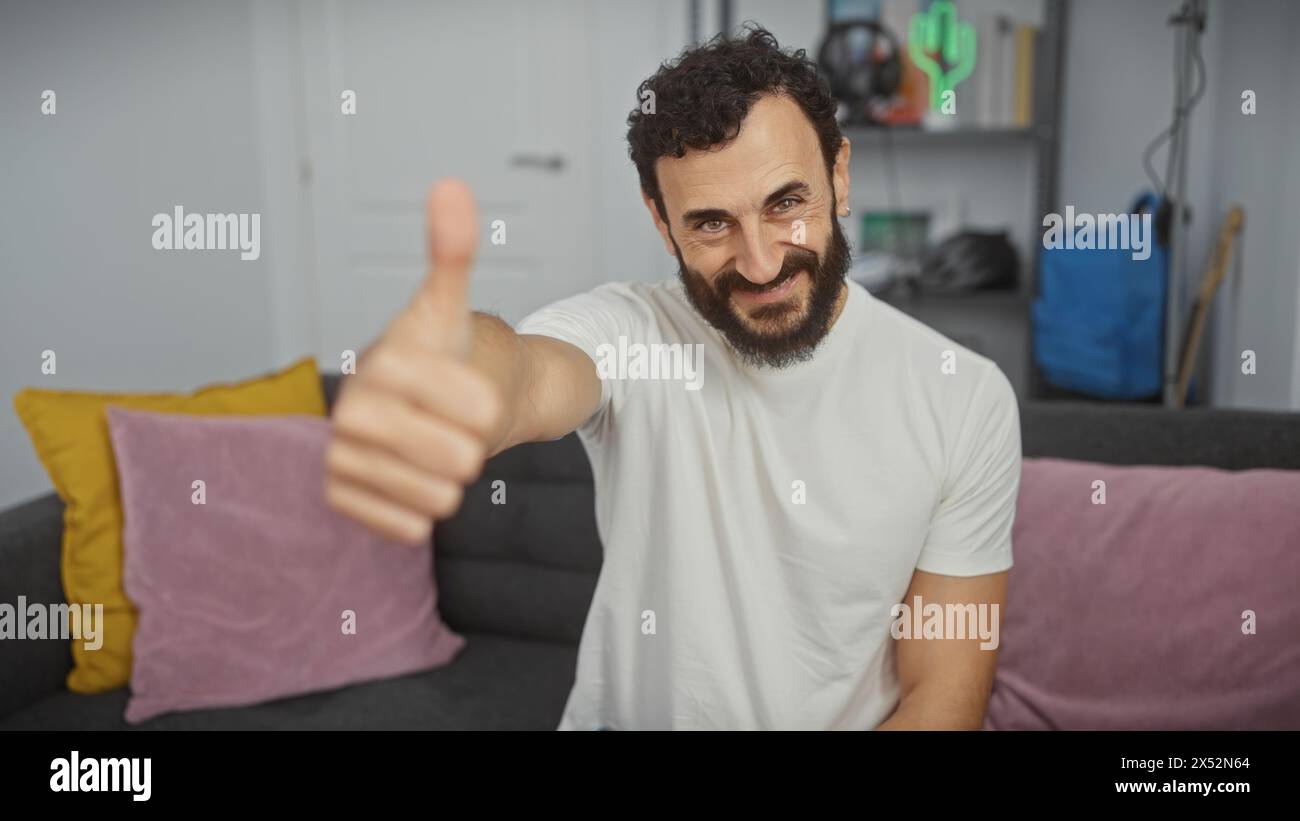 Homme barbu dans le salon donnant les pouces Banque D'Images