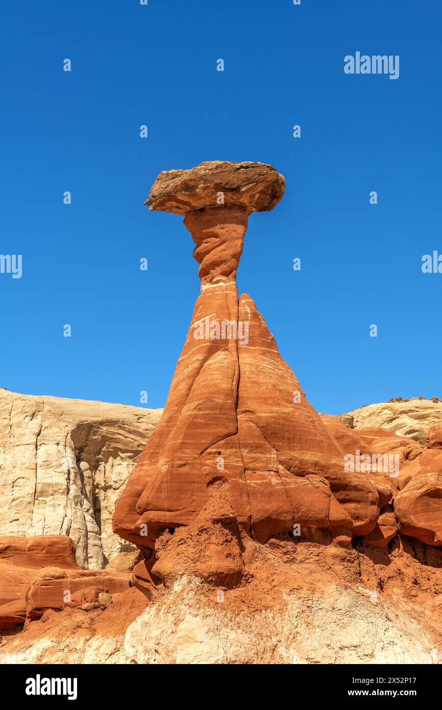 Hoodoo en toadstool en grès blanc et rouge à Kanab Utah montrant des flèches fortement érodées et une roche plus dure équilibrée sur le dessus encadrée par un ciel bleu. Banque D'Images