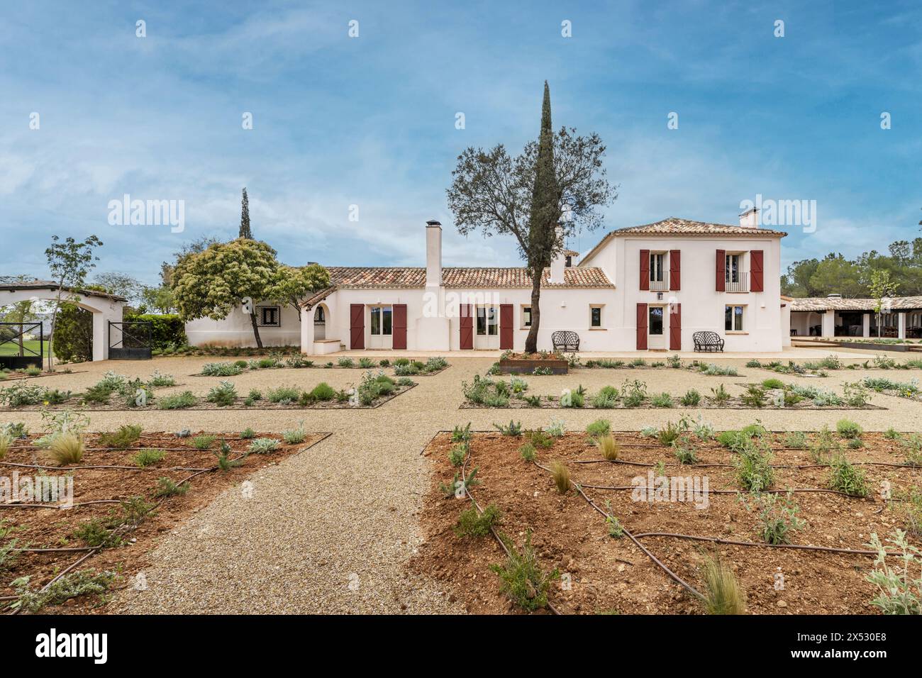 Une ferme de construction de style andalou avec des façades blanches et des volets en bois rouge et des jardins nouvellement plantés Banque D'Images