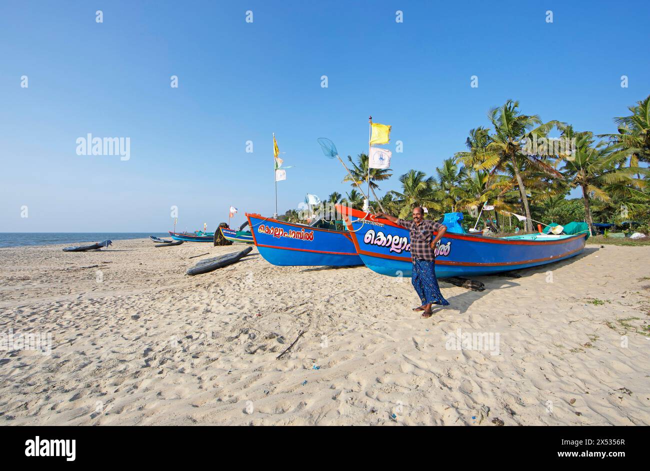 Pêcheur indien, 42 ans, et bateaux de pêche colorés à Marari Beach ou Beach, Mararikulam, district d'Alappuzha, Kerala, Inde Banque D'Images