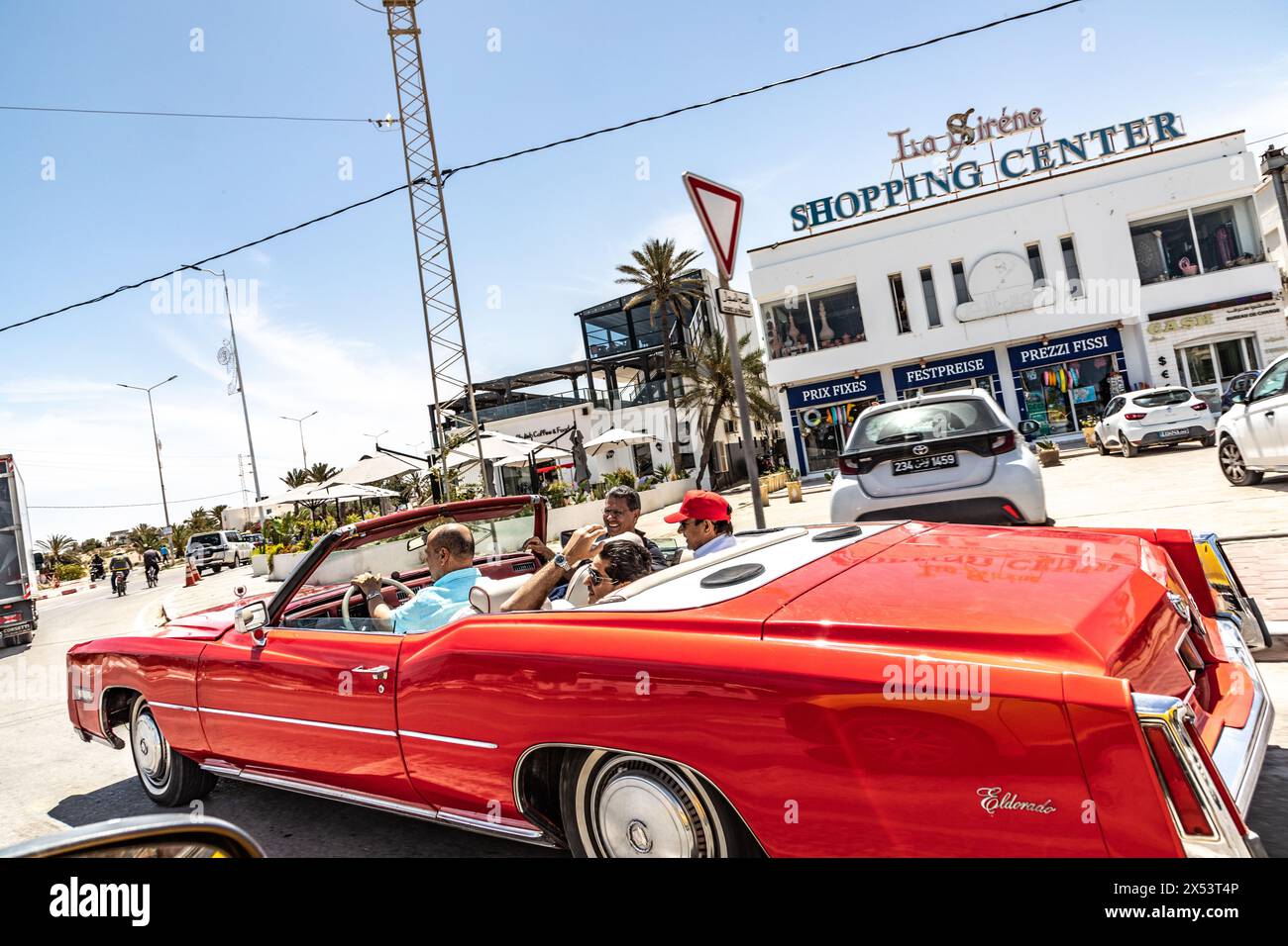 Djerba, Tunisie - 3 mai 2024 : les arabes apprécient la croisière avec une cadillac Eldorado rouge à Djerba, Tunisie. Banque D'Images
