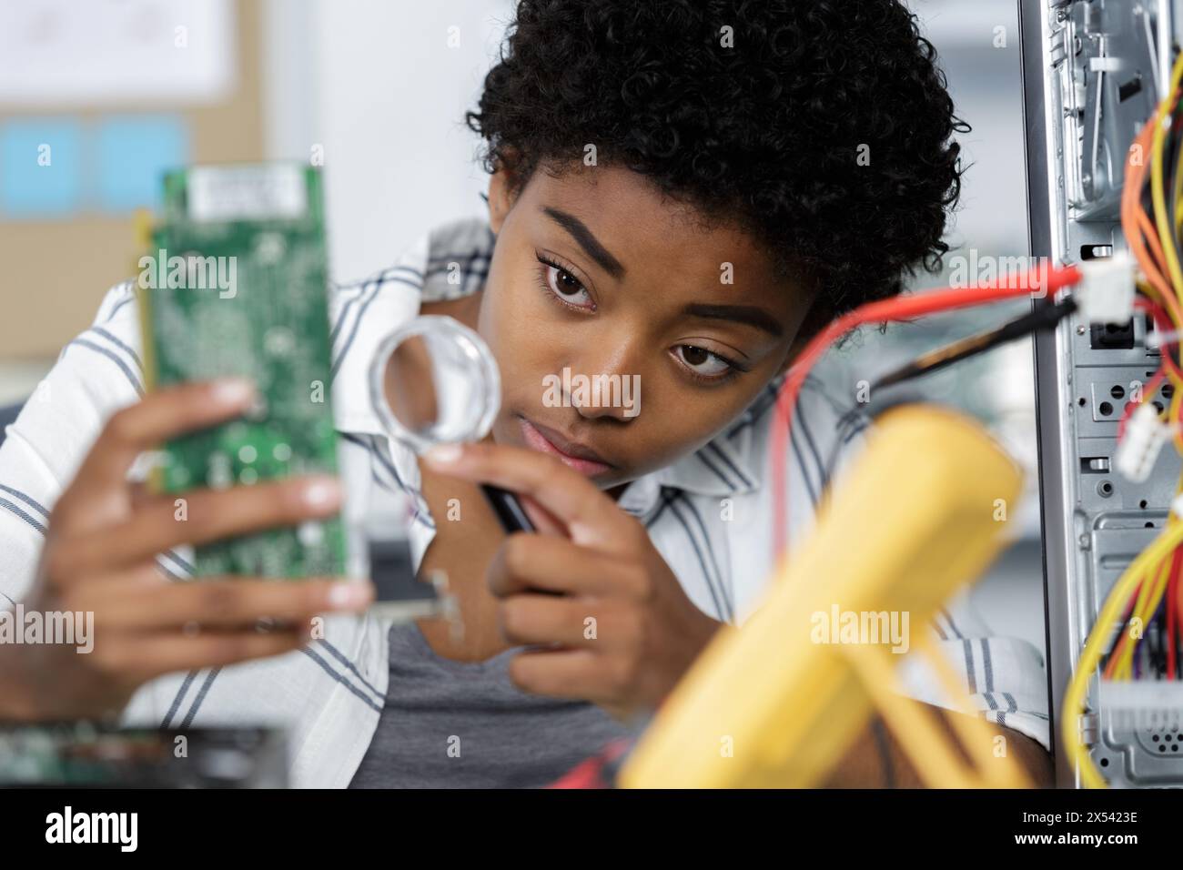 femme sérieuse travaillant avec le circuit imprimé avec la loupe Banque D'Images