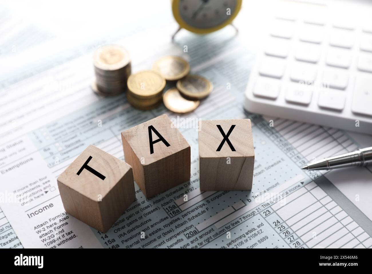 Cubes en bois avec le mot taxe, calculatrice, pièces de monnaie et stylo sur le document, gros plan Banque D'Images