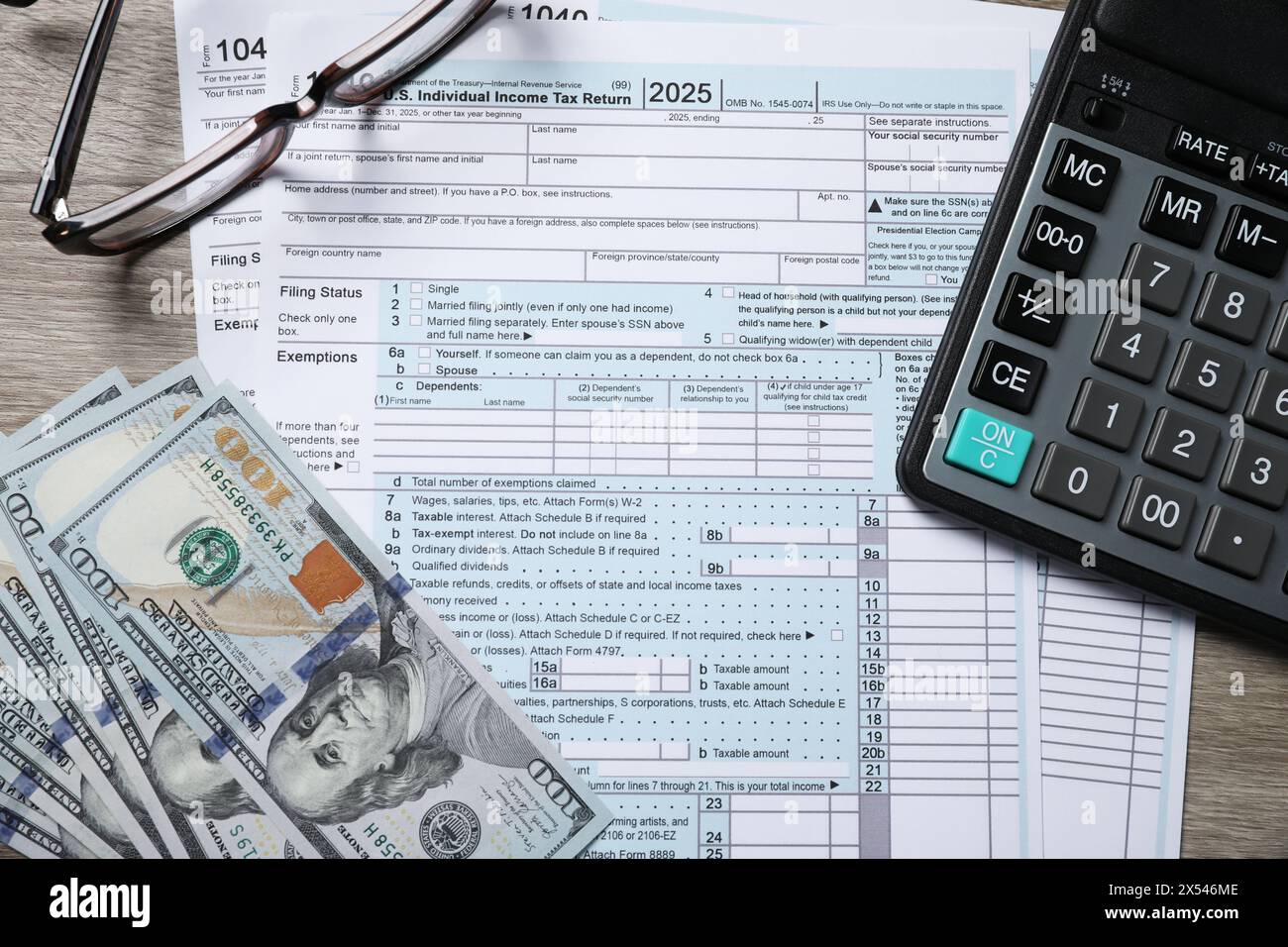 Paie. Formulaires de déclaration d'impôt, billets de banque en dollars, lunettes et calculatrice sur table en bois, pose à plat Banque D'Images