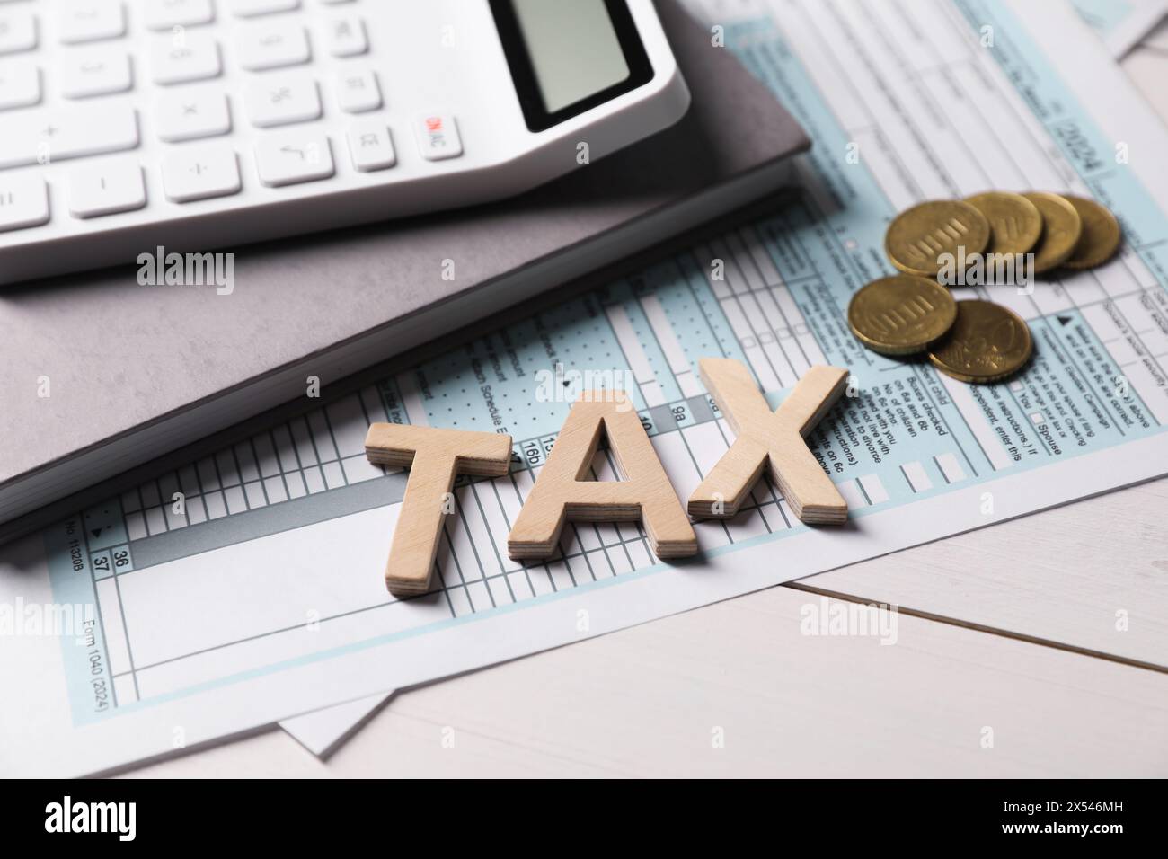 Word Tax fait avec des lettres, calculatrice, document, cahier et pièces de monnaie sur la table en bois blanc, gros plan Banque D'Images