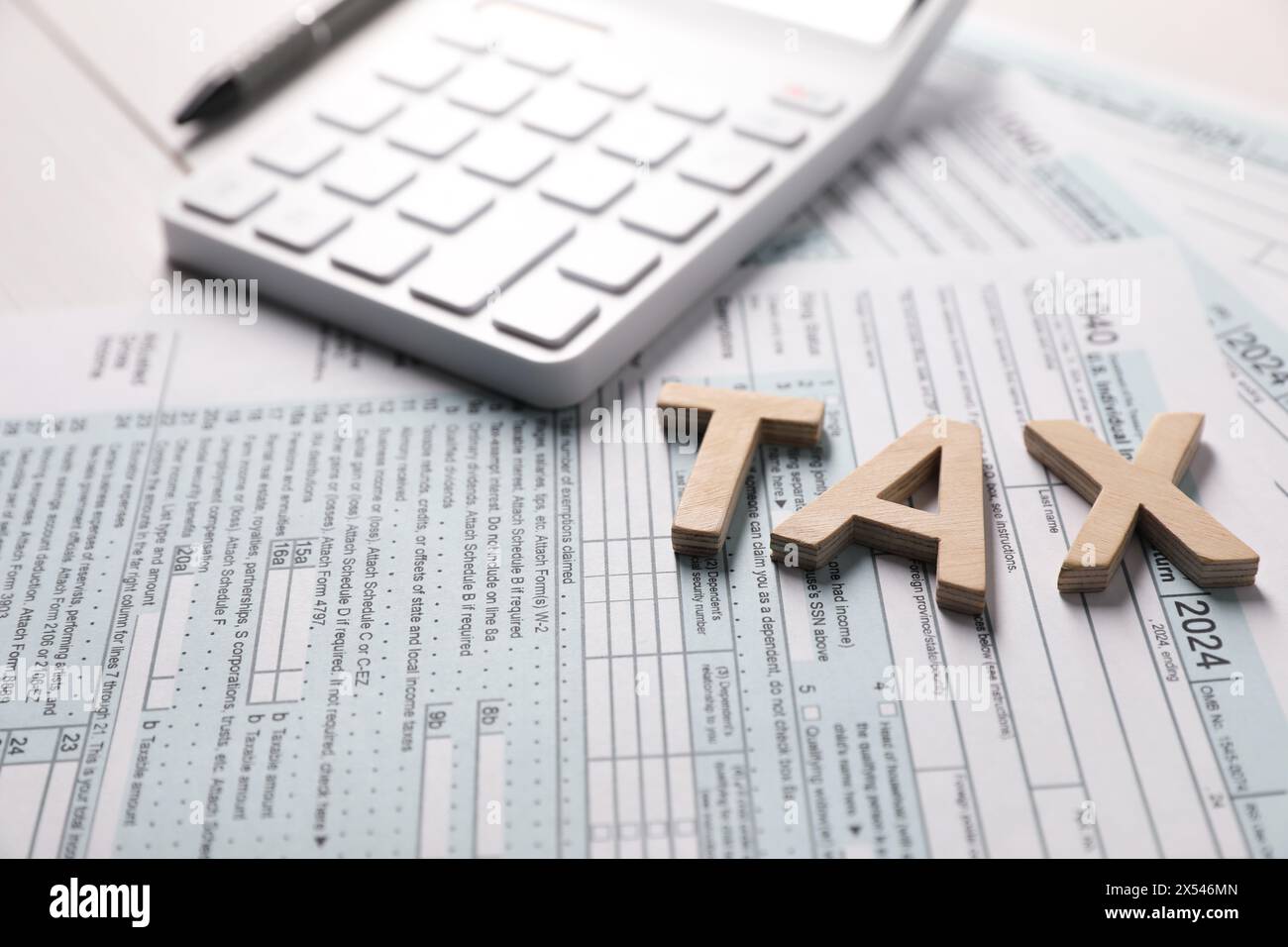 Word Tax fait avec des lettres en bois, calculatrice et documents sur la table, gros plan Banque D'Images