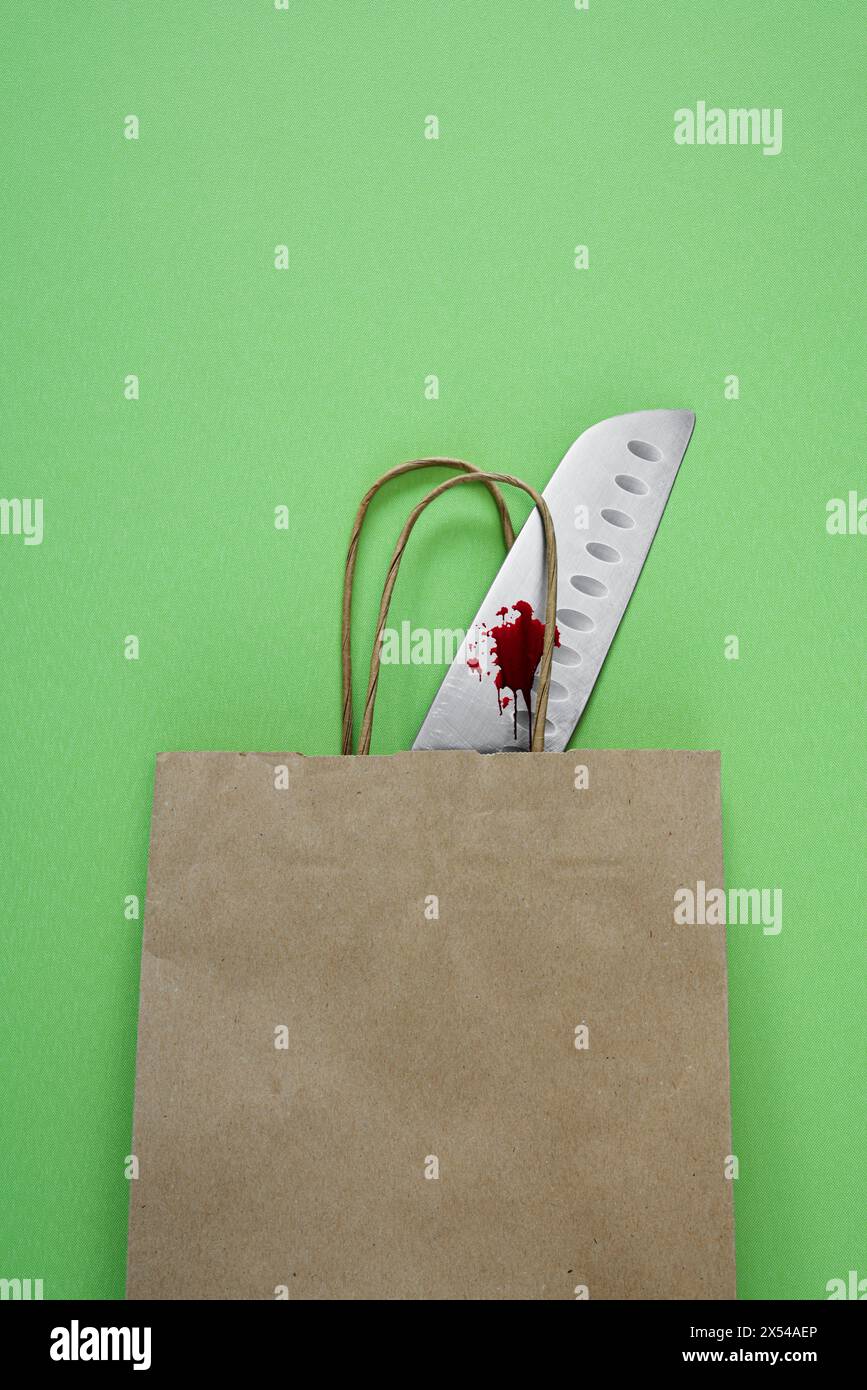 Couteau de cuisine sanglant dans un sac en papier brun. Banque D'Images