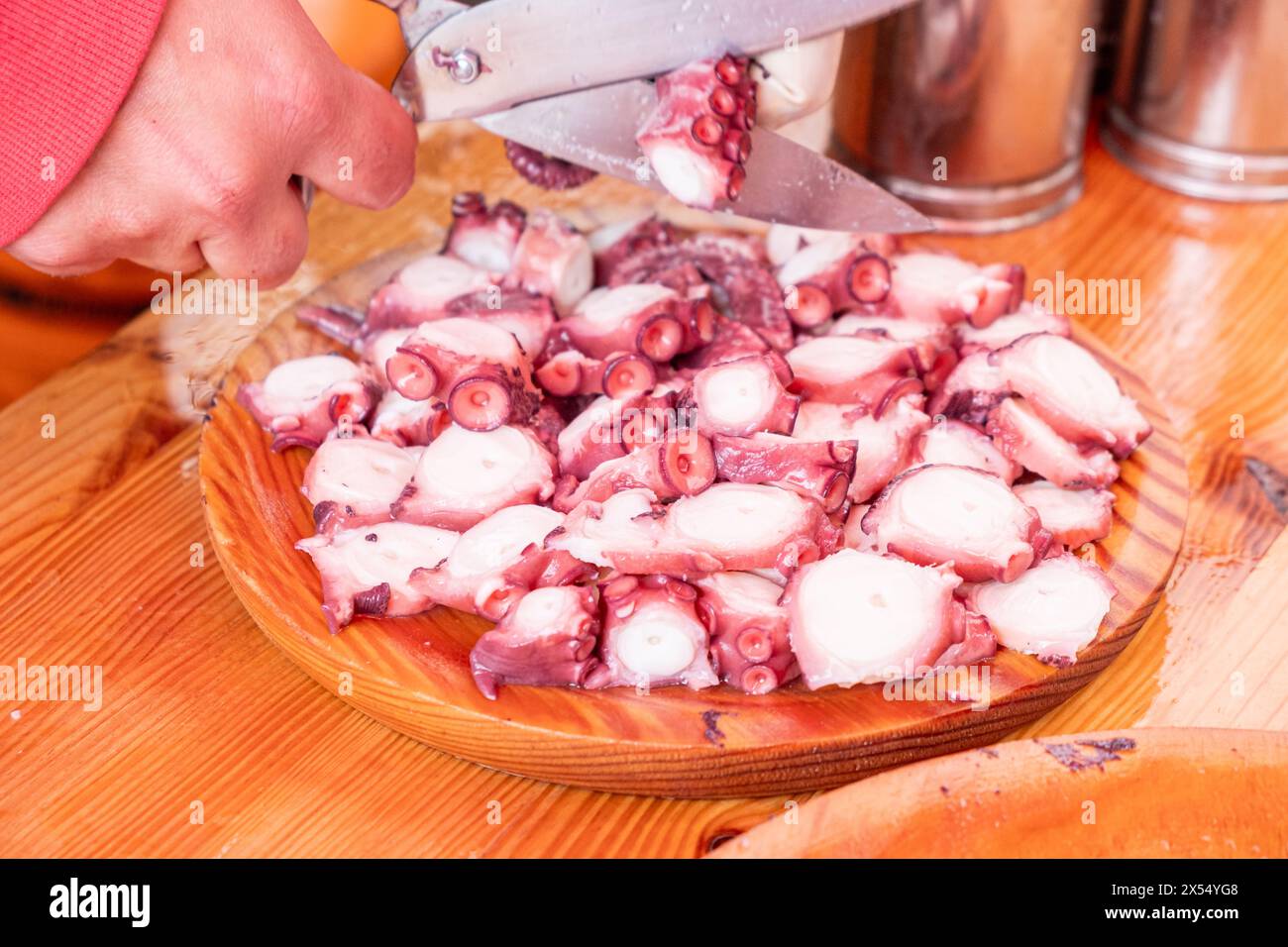 mains d'une personne coupant des tentacules de pieuvre préparant une ration de pieuvre. Pulpo a feira. Galice, nord de l'Espagne Banque D'Images