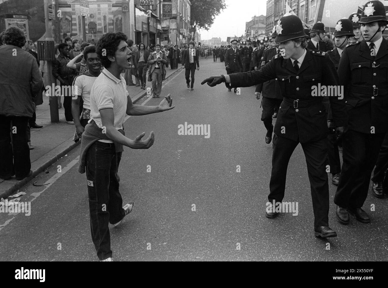 La police affronte un jeune noir. La police protège les membres du Front national de droite – derrière le cordon policier des manifestants de gauche qui protestent contre la marche NF. 500 membres du Front national ont défilé de New Cross à Lewisham, diverses contre-manifestations d'environ 4 000 personnes ont provoqué de violents affrontements entre les deux groupes et entre les manifestants anti-NF et la police. Londres, Angleterre 13 août 1977. Années 1970 Royaume-Uni HOMER SYKES Banque D'Images