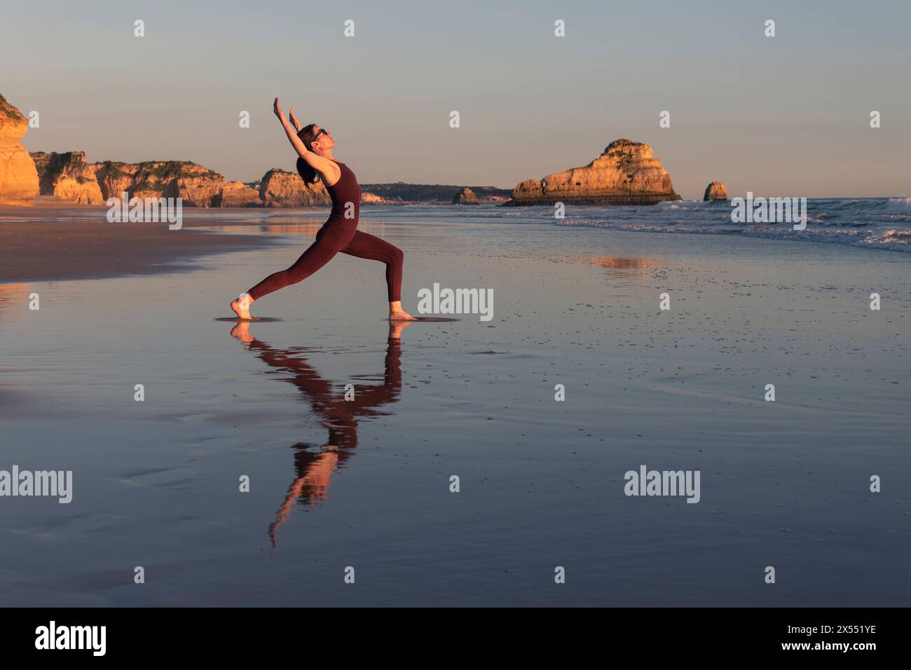 Femme étirant et pratiquant le yoga à la plage au lever du soleil Banque D'Images